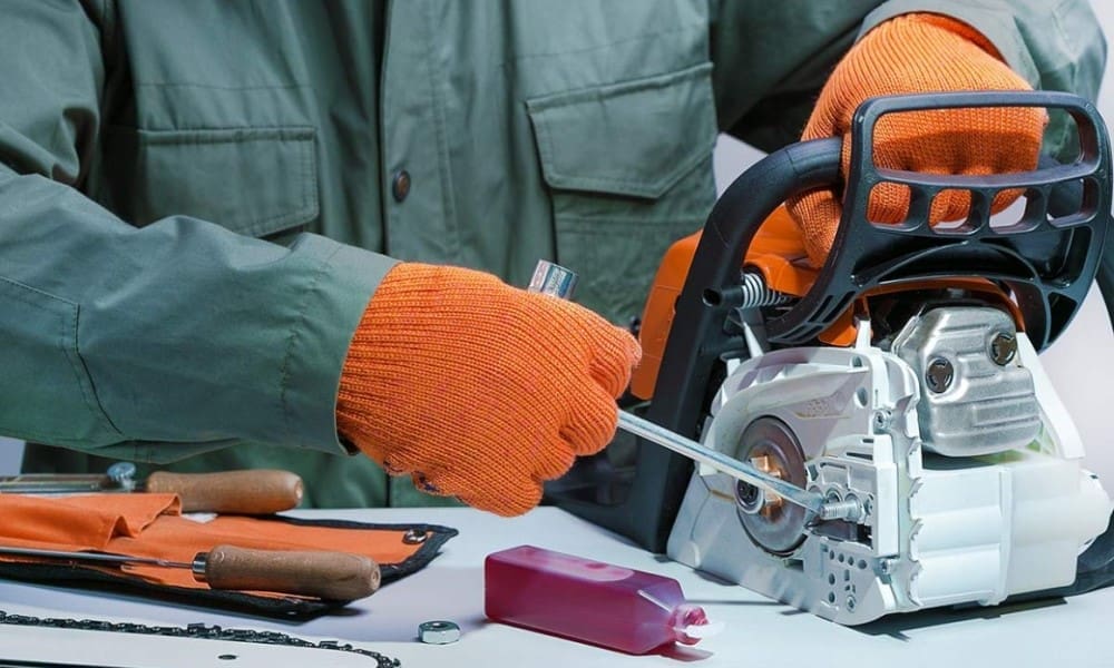 Person in safety gear maintaining a chainsaw — inspecting, cleaning, adjusting or servicing components such as the chain and bar — in a workshop or outdoor setting to ensure safe, reliable operation.