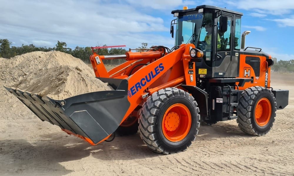 Wheeled front end loader with operator in cab moving soil on a civil construction training site during RIIMPO321F Conduct Civil Construction Wheeled Front End Loader Operations practical course