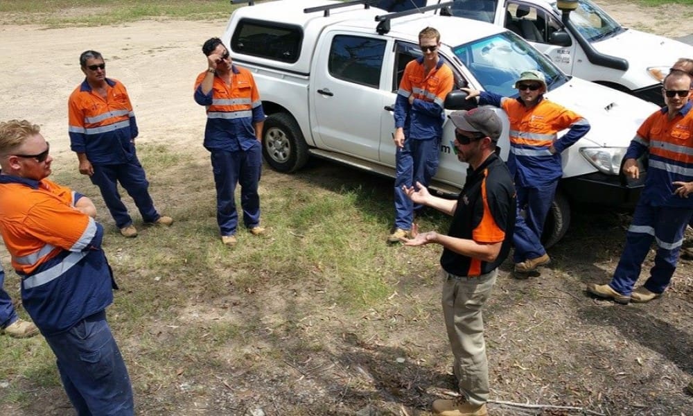 Four‑wheel‑drive vehicle (4WD) on rugged outdoor terrain with a person in safety gear standing nearby, illustrating practical 4WD operation and maintenance training.