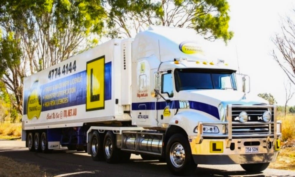 Truck driving instructor and student practising driving a heavy combination vehicle (prime mover with trailer) on a training site as part of TLIC3005 course.